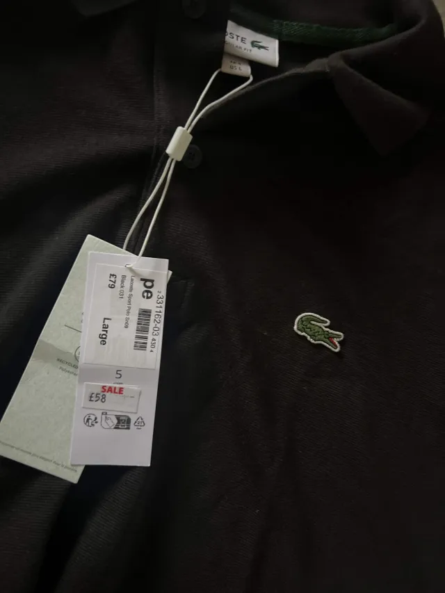 A black Lacoste polo shirt with its shop tags still on